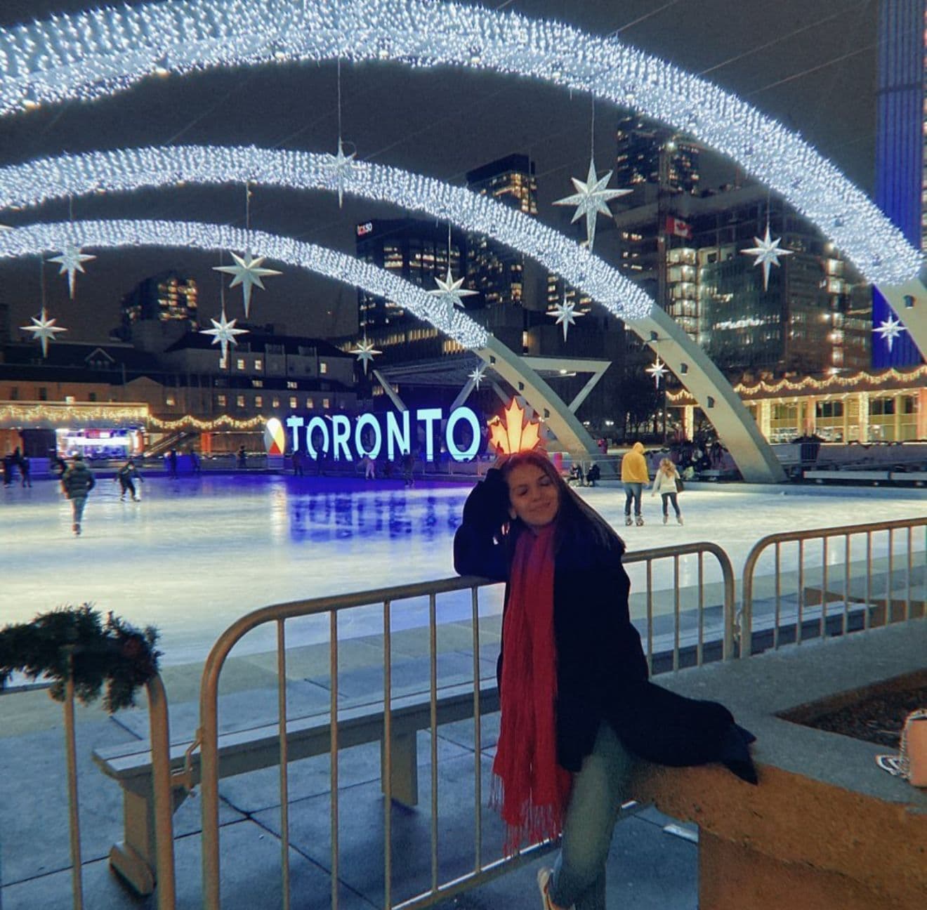 Jaqueline em Nathan Phillips Square, Toronto — luzes de inverno e o letreiro TORONTO ao fundo